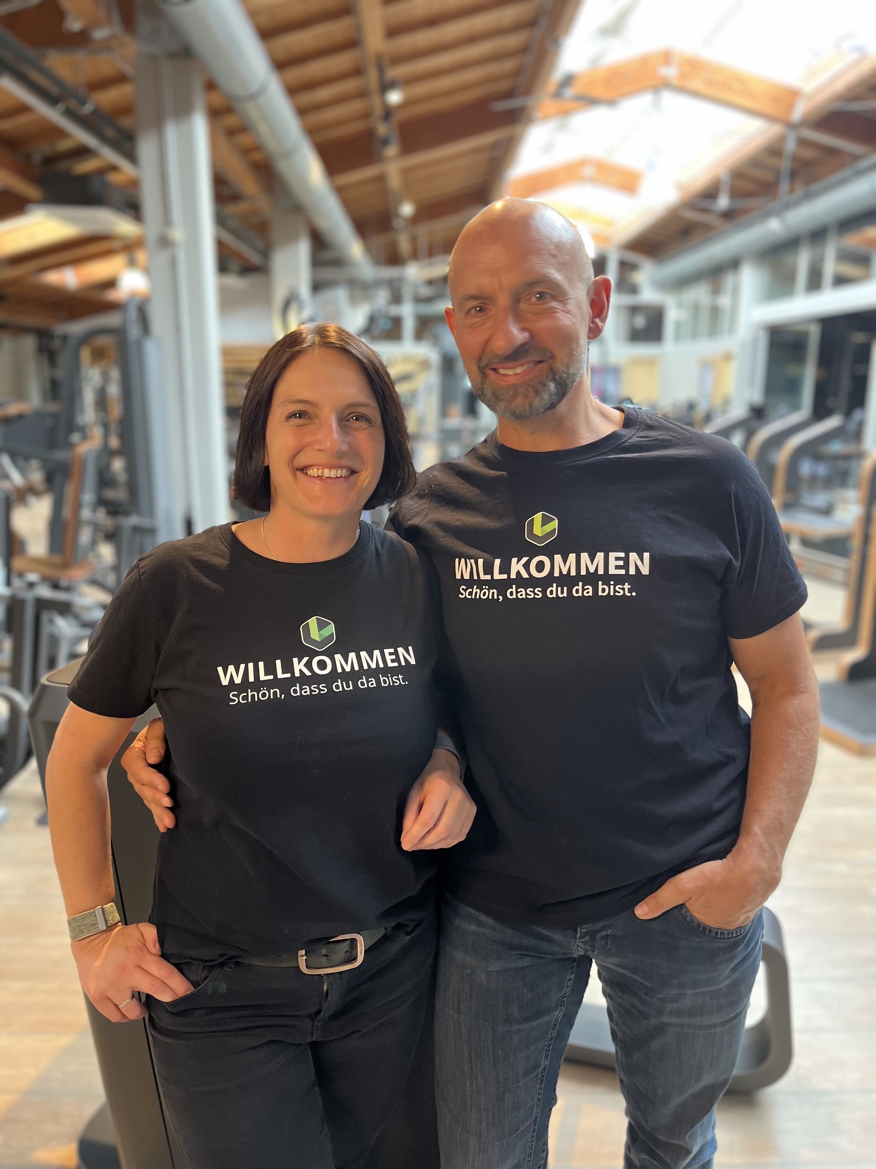 Professional health coaches and gym owners, a husband and wife team standing in a modern boutique fitness studio